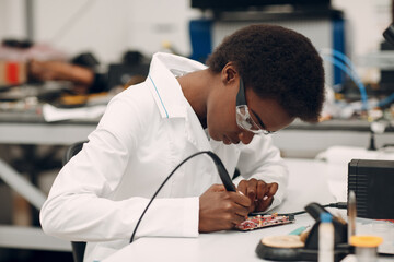 Scientist african american woman working in laboratory with soldering iron. Research and...