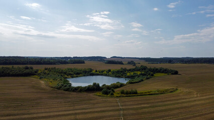 Fototapeta na wymiar Aerial view of the lake in agro fields. Rustic landscape