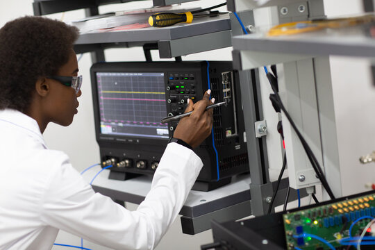 Scientist African American Woman Working In Laboratory With Oscilloscope Electronic Tech. Research And Development Of Electronic Devices By Color Black Woman.