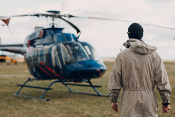 Portrait of helicopter pilot standing near vehicle in field airport.
