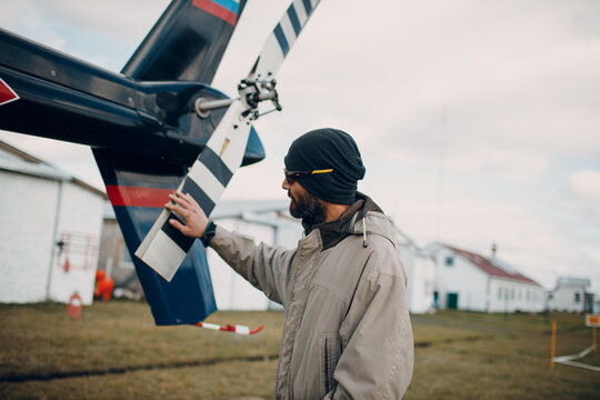 Portrait of helicopter pilot standing near vehicle in field airport.