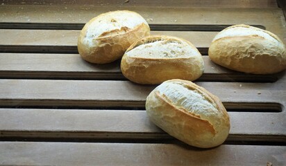 Frische goldgelbe Brötchen auf brauner Lattenholzfläche in Bäckerei
