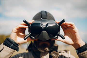Man controlling fpv quadcopter drone for aerial photography and videography with goggles antenna remote controller.