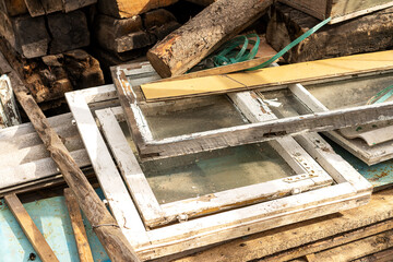 A dump of old wooden window frames with glass. Recycling of materials, environmental problems and collection of waste and construction waste