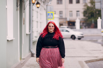 European plus size woman. Young red pink haired body positive girl walk at city street outdoors