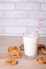 Flatlay an after school snack of chocolate chip cookies and an glass cup of milk. The cookies with chocolate drops and on a rustic wood kitchen table, with copy space. yummy and tasty