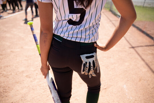 Middle school girl softball player stretching with bat in batter