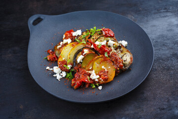 Modern style traditional Greek briam with sliced vegetable, potatoes and feta cheese served as...