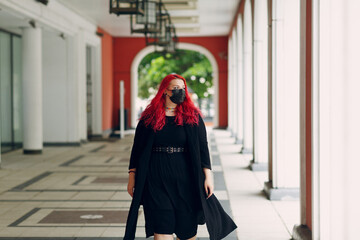 European plus size woman walking outdoor street city. Young red pink haired body positive girl.
