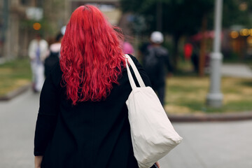 European plus size woman walking outdoor street city. Young red pink haired body positive girl.