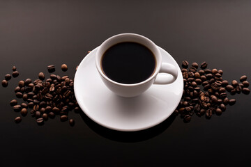 white cup with dark coffee and beans on black background