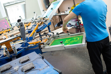 Serigraphy silk screen print process at clothes factory. Carousel Frame, squeegee and plastisol...