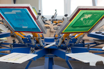 Serigraphy silk screen print process at clothes factory. Frame, squeegee and carousel.