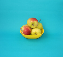 Ripe apples in a yellow basket on a blue background.