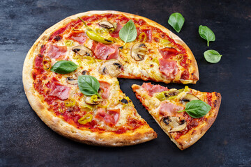 Traditional Italian pizza prosciutto e funghi with ham, mushrooms and mozzarella served as close-up...