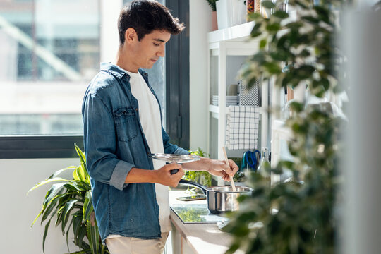 Handsome young man cooking in the kitchen at home