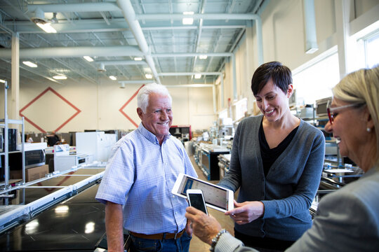 Saleswoman helping senior couple with digital tablet in appliance store