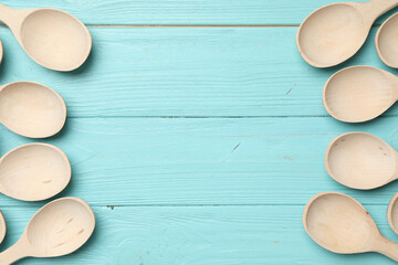 New wooden spoons on light blue wooden table, flat lay with space for text. Cooking utensils
