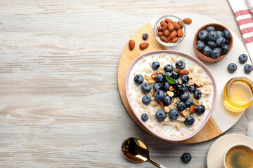 Flat lay composition with tasty oatmeal porridge and ingredients served on wooden table. Space for text