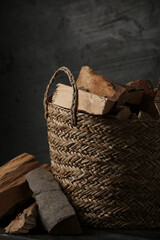 Wicker basket with cut firewood on black table