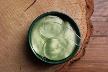 Package of under eye patches on wooden table, top view. Cosmetic product