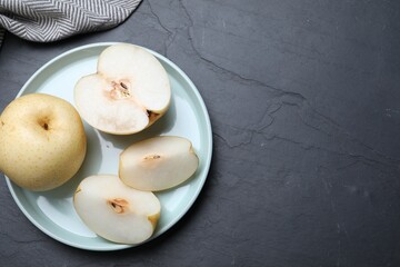 Cut and whole apple pears on black table, flat lay. Space for text