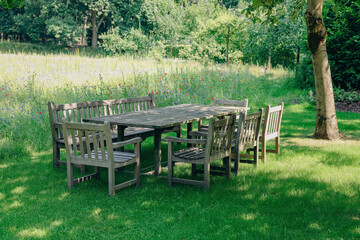 Empty wooden table with bench and chairs on sunny day outdoors