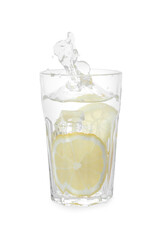 Water with sliced lemon splashing out of glass on white background