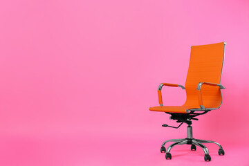 Comfortable office chair on pink background, space for text