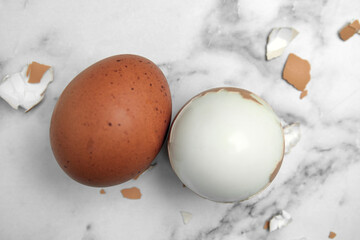 Boiled eggs and pieces of shell on white marble table, flat lay