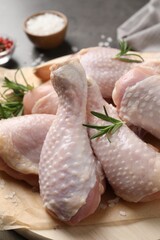 Wooden board with fresh raw chicken legs and other products on grey table