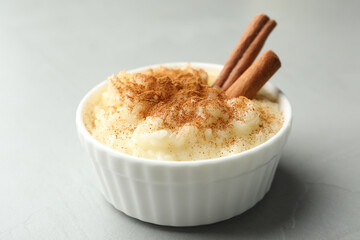 Delicious rice pudding with cinnamon on light table, closeup