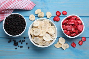 Bowls and dried fruits on turquoise wooden table, flat lay