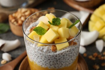 Delicious chia pudding with mango, mint and granola in glass, closeup