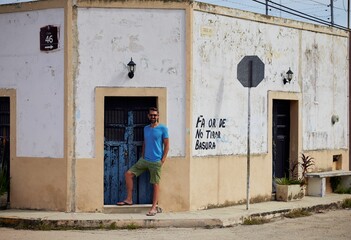 Closeup of a man standing near an old blue door in Valladolid, Yucatan, Mexico - obrazy, fototapety, plakaty