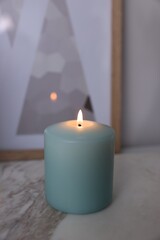 Fototapeta na wymiar Beautiful burning candle on marble table, closeup