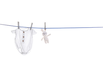 Baby onesie and toy bunny drying on laundry line against white background