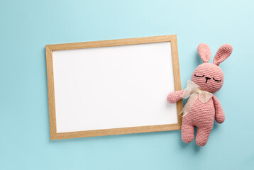 Blank white board with toy bunny on turquoise background, flat lay. Space for text