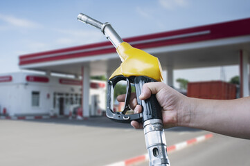 Man holds a refueling gun in his hand for refueling cars. Gas station with diesel and gasoline fuel...