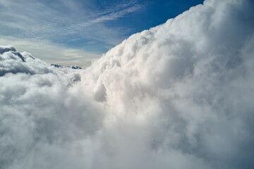Aerial view from airplane window at high altitude of earth covered with white puffy cumulus clouds
