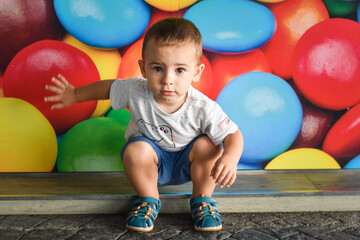 Niño bebé expresivo frente a un fondo de caramelos de colores - obrazy, fototapety, plakaty