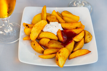 Appetizing Spanish dish Patatas bravas, baked potatoes traditionally topped with spicy sauces..