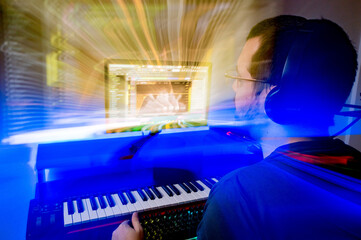 rear view of man in his home music studio with lights painting around the computer monitor.