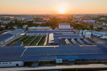 Aerial view of solar power plant with blue photovoltaic panels mounted on industrial building roof...