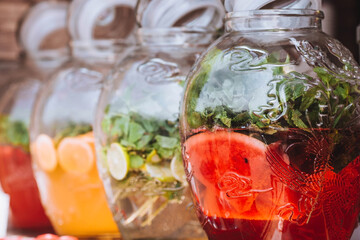 Glass jars with lemonade made of lime, lemon, orange, watermelon, mint at a street food kiosk. A refreshing summer drink.