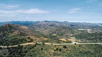 Fototapeta na wymiar Empty long mountain road to the horizon on a sunny summer day at bright sunset - aerial drone shot