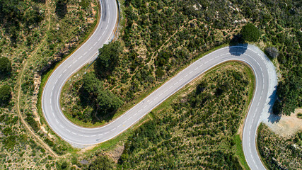 Empty long mountain road to the horizon on a sunny summer day at bright sunset - aerial drone shot