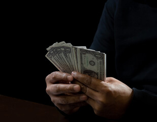 The hands of a man wearing a black shirt, sitting on a chair and a table, is a thief, holding...