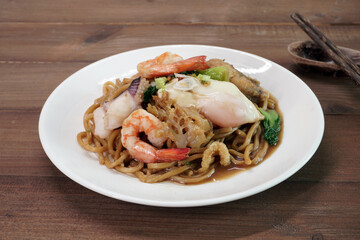 Hokkien Mee (Mee Pad Hokkien) the famous Stir-fried  seafood Noodles. Phuket Original Hokkien Noodles consists of thick yellow (egg) noodles fried with seafood, pork and vegetables. Selective focus