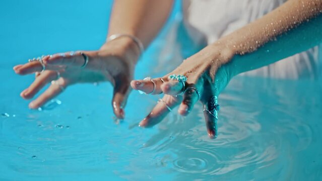 Woman in water imitates playing music on piano. Boho jewelry, rings with stones on fingers. Girl in white dress swimming in pool or lake. Femininity, trend, hippie style concept.